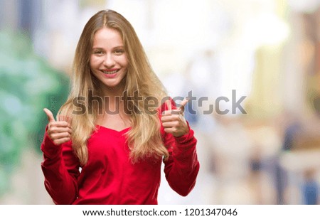 Young beautiful blonde woman wearing red sweater over isolated background success sign doing positive gesture with hand, thumbs up smiling and happy. Looking at the camera with cheerful expression