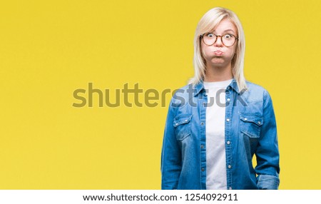 Young beautiful blonde woman wearing glasses over isolated background puffing cheeks with funny face. Mouth inflated with air, crazy expression.