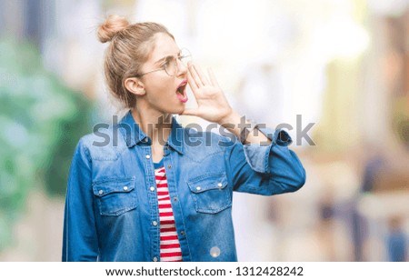 Young beautiful blonde woman wearing glasses over isolated background shouting and screaming loud to side with hand on mouth. Communication concept.
