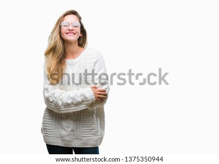 Young beautiful blonde woman wearing winter sweater and sunglasses over isolated background happy face smiling with crossed arms looking at the camera. Positive person.