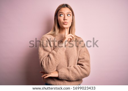 Young beautiful blonde woman wearing winter wool sweater over pink isolated background Thinking concentrated about doubt with finger on chin and looking up wondering