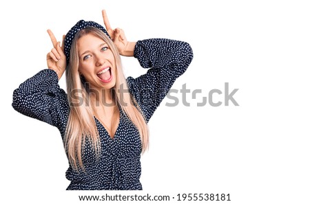 Young beautiful blonde woman wearing casual clothes posing funny and crazy with fingers on head as bunny ears, smiling cheerful 