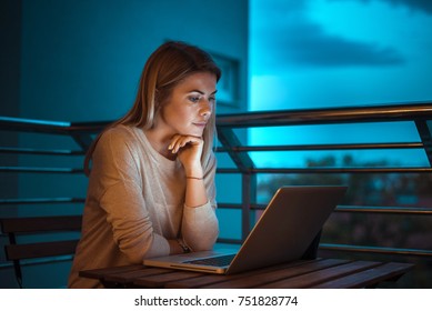 Young Beautiful Blonde Woman Working On Laptop At Night. High ISO Image.