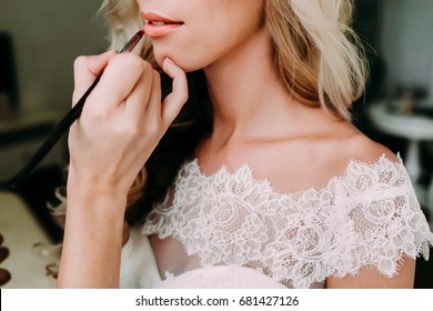 Young beautiful bride applying wedding make-up by make-up artist. Morning preparation. Close-up hands near face - Powered by Shutterstock