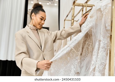 Una joven novia hermosa examina cuidadosamente un vestido de novia en un estante
