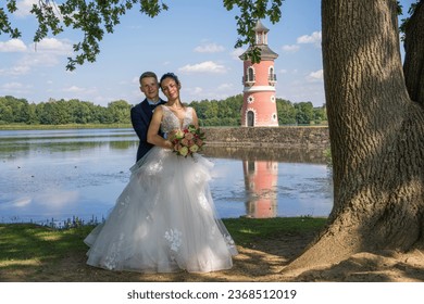 
Young beautiful bride and groom stand in front of the water against the backdrop of a pink lighthouse. Newlyweds on a walk. Wedding, love, married couple  - Powered by Shutterstock