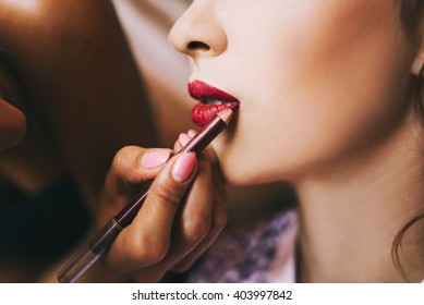 Young Beautiful Bride In A Satin Dressing Gown Doing Makeup With Burgundy Lipstick