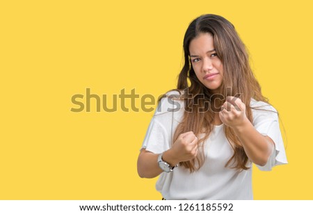 Young beautiful brunette business woman over isolated background Ready to fight with fist defense gesture, angry and upset face, afraid of problem