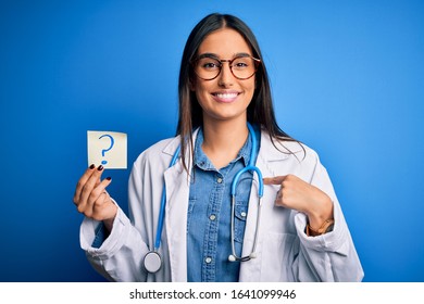 Young Beautiful Brunette Doctor Woman Holding Paper With Question Mark Symbol Message With Surprise Face Pointing Finger To Himself