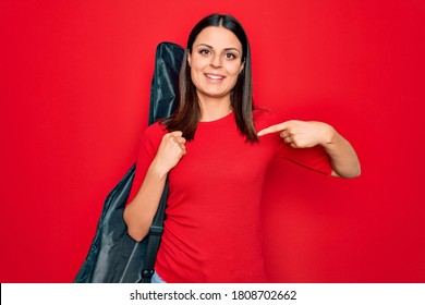 Young Beautiful Brunette Guitarist Woman Holding Guitar Case Over Isolated Red Background Pointing Finger To One Self Smiling Happy And Proud