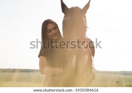 Young beautiful brunette with a horse in the nature