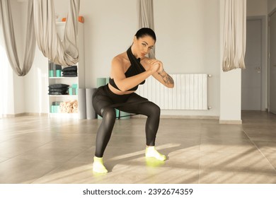 Young beautiful brunette sporty athletic woman squats with fitness elves in the gym.  - Powered by Shutterstock