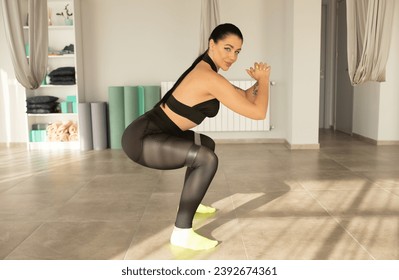 Young beautiful brunette sporty athletic woman squats with fitness elves in the gym.  - Powered by Shutterstock