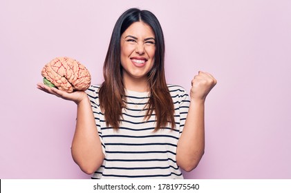 Young Beautiful Brunette Woman Asking For Memory Healthy And Mental Care Holding Brain Screaming Proud, Celebrating Victory And Success Very Excited With Raised Arm