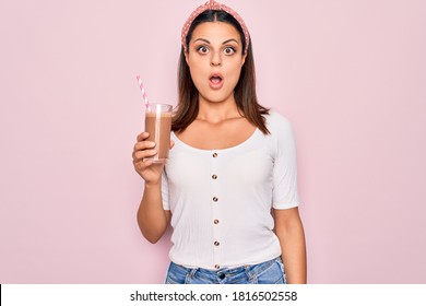 Young beautiful brunette woman drinking glass of chocolate beverage using straw scared and amazed with open mouth for surprise, disbelief face