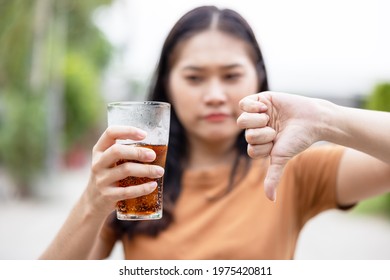 Young beautiful brunette woman drinking glass with cola refreshment using straw with angry face, negative sign showing dislike with thumbs down, rejection concept