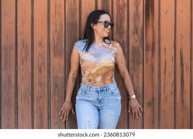 Young and beautiful brunette woman, latin and with sunglasses, dresses casually. The girl is leaning against a wooden door and is doing different body postures. Concept expressions - Powered by Shutterstock