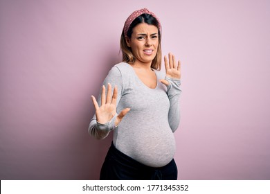 Young Beautiful Brunette Woman Pregnant Expecting Baby Over Isolated Pink Background Disgusted Expression, Displeased And Fearful Doing Disgust Face Because Aversion Reaction. With Hands Raised