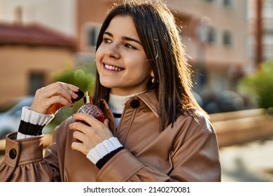 Young beautiful brunette woman smiling happy applying fragance from luxury perfume