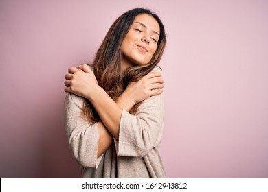 Young beautiful brunette woman wearing casual sweater standing over pink background Hugging oneself happy and positive, smiling confident. Self love and self care - Shutterstock ID 1642943812