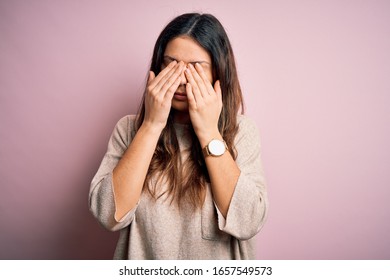 Young beautiful brunette woman wearing casual sweater standing over pink background rubbing eyes for fatigue and headache, sleepy and tired expression. Vision problem