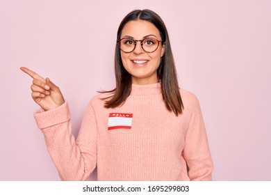 Young Beautiful Brunette Woman Wearing Sticker With Hello My Name Is Message Smiling Happy Pointing With Hand And Finger To The Side