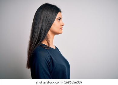 Young beautiful brunette woman wearing casual sweater standing over white background looking to side, relax profile pose with natural face with confident smile.