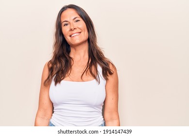 Young beautiful brunette woman wearing casual t-shirt standing over isolated white background smiling and looking at the camera pointing with two hands and fingers to the side.