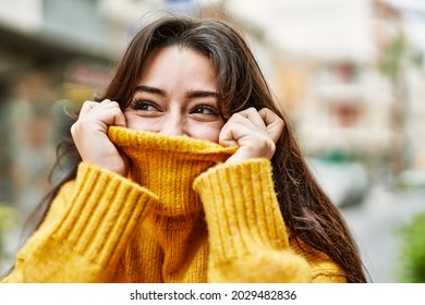 Young beautiful brunette woman wearing turtleneck sweater doing funny gesture covering face with sweater - Shutterstock ID 2029482836
