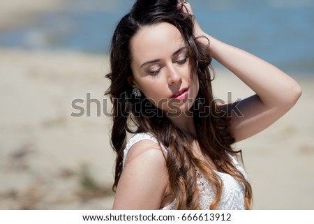 Young beautiful brunette woman in white dress on the seashore. portrait with closed eyes