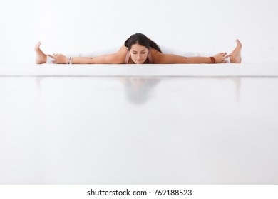 Young Beautiful Brunette Woman Yoga Instructor Doing Twine And Stretching Exercise Lying On Floor On White Isolated Background