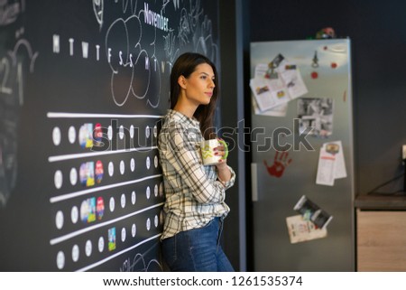 Young beautiful business woman holding her mug and smiling in the kitchen 