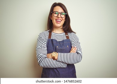 Young beautiful business woman wearing store uniform apron over isolated background happy face smiling with crossed arms looking at the camera. Positive person.