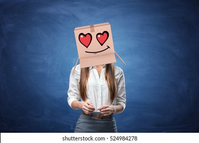 Young beautiful businesswoman with cardboard box on her head with drawn smiley face with hearts instead of eyes. Anonymous person. Falling in love. Office romance. Love customers. - Powered by Shutterstock