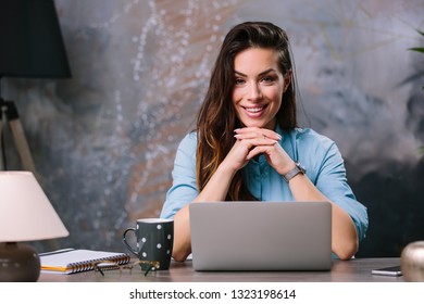 Young beautiful businesswoman in glasses working on laptop while sitting at her working place