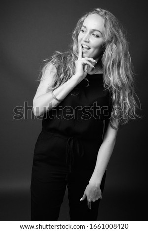 Young beautiful businesswoman with long wavy blond hair against gray background