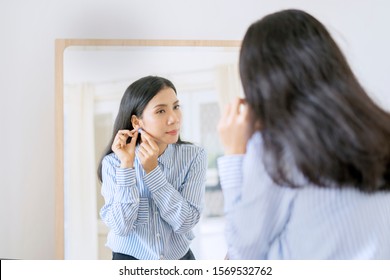 Young Beautiful Businesswoman Putting On Her Earrings In Front Of Mirror Getting Ready For Work