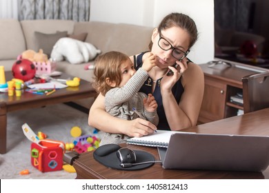 Young beautiful businesswoman talking on mobile phone and working on a laptop. Mother playing with child during working. Childcare and work concept. Women powerful.