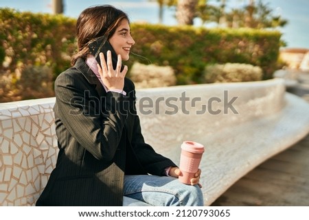 Young beautiful businesswoman talking on the smartphone and drinking coffee at the city.