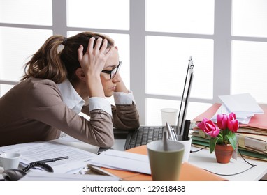 Young And Beautiful Businesswoman Tired From Work In The Office.Woman Holding Her Head