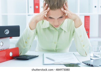 Young and beautiful businesswoman tired from work in the office. Woman holding her head. Busy schedule concept.