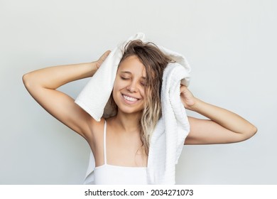 A Young Beautiful Caucasian Blonde Smiling Woman Dry Her Wet Hair With A White Towel On Her Head After A Shower Isolated On A White Background. Hair Care