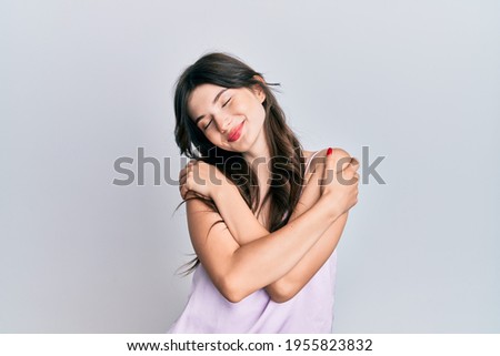 Young beautiful caucasian girl wearing casual clothes hugging oneself happy and positive, smiling confident. self love and self care 