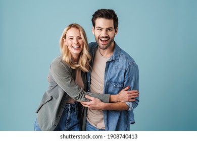 Young Beautiful Caucasian Man And Woman Smiling And Hugging At Camera Isolated Over Blue Background