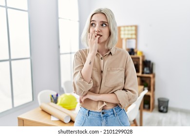 Young beautiful caucasian woman at construction office looking stressed and nervous with hands on mouth biting nails. anxiety problem. 