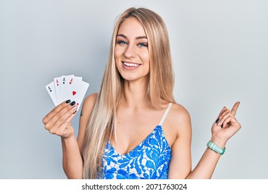 Young Beautiful Caucasian Woman Holding Poker Cards Smiling Happy Pointing With Hand And Finger To The Side 