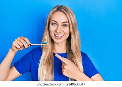 Young beautiful caucasian woman holding toothbrush with toothpaste smiling happy pointing with hand and finger  - Powered by Shutterstock