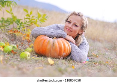 Young beautiful caucasian woman lying on the pumpkin outdoors
