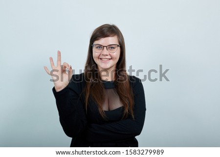 Young beautiful caucasian woman showing ok sign gesture wearing casual black shirt on isolated gray background