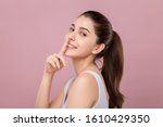 Young beautiful Caucasian woman with smiley face touching her nose, surgery nose job concept, isolated on pink background.